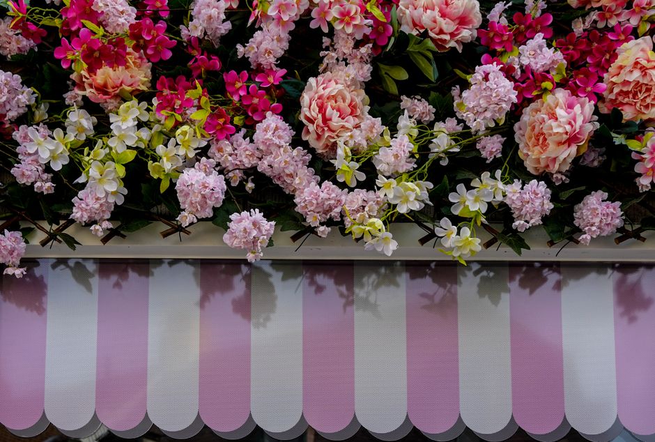 A floral arrangement featuring a variety of fresh flowers including pink carnations, hydrangeas, white and yellow orchids, and bright pink blossoms, all densely packed together. The flowers are arrang